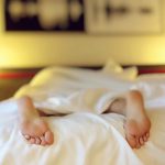 person lying on bed covering white blanket